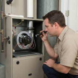 HVAC technician inspects the internal blower motor inside an open furnace panel