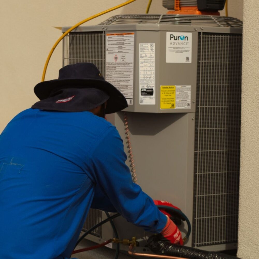 Technician gently working on an outdoor HVAC unit.